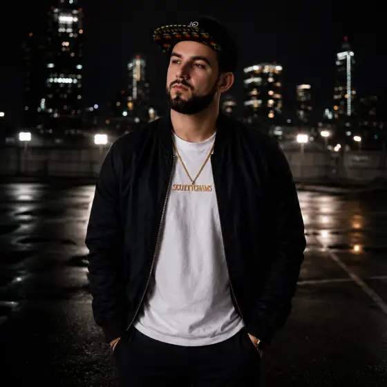 Scottychams posing against a graffiti-tagged brick wall